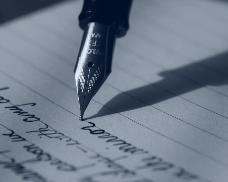 A fountain pen resting on a page of handwriting.