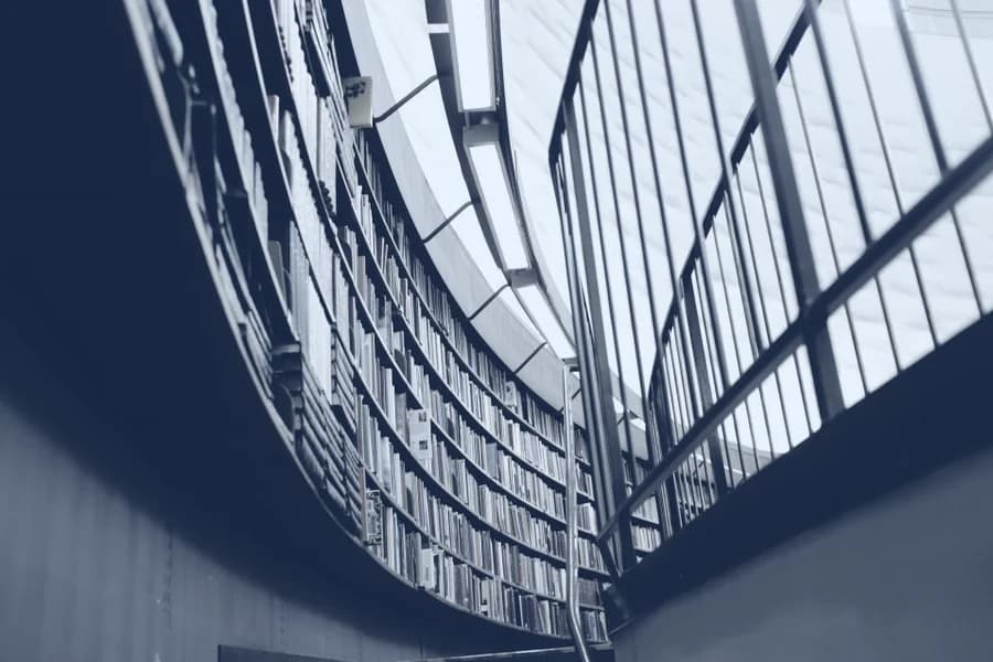 A library reading room seen from above, shelves curving away below a skylight.